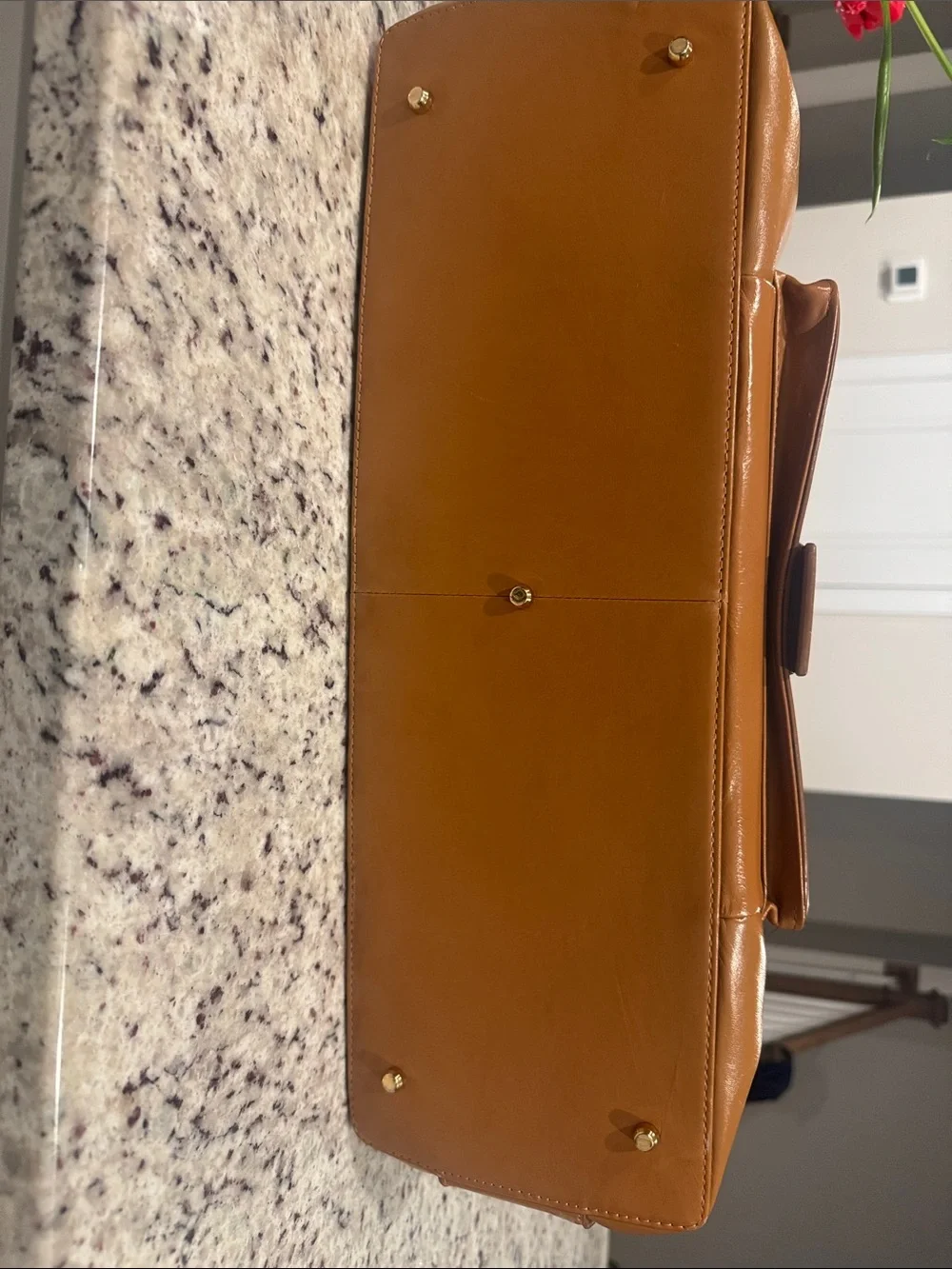 The Find Classic Tan Leather Weekender Travel Bag with Gold Hardware Buckle.